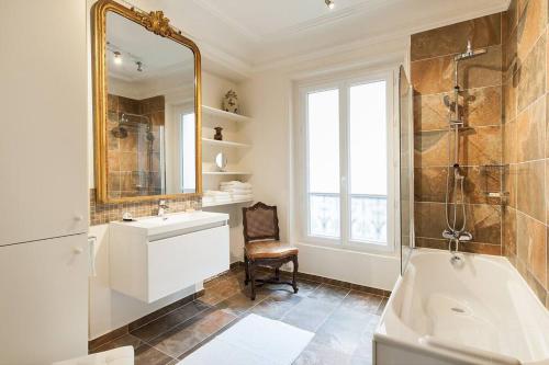 une salle de bain avec une baignoire, un lavabo et un miroir dans l'établissement CAVALIER DES LIONS 2bed 2 and half baths, à Paris