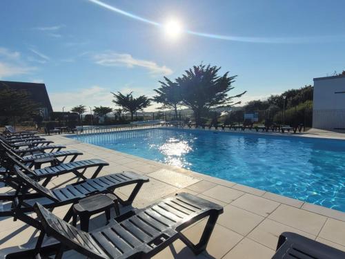 - une piscine bordée de chaises longues dans l'établissement Gîte de l'océan, vue mer avec piscine, à Guidel-Plage