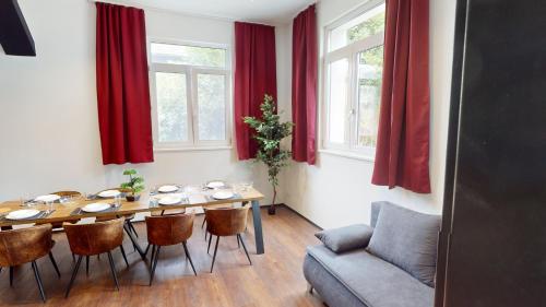 a dining room with a table and red curtains at CROWN LIVING Design Loft, Küche, Bibliothek, Gartensitzplatz in Lustenau