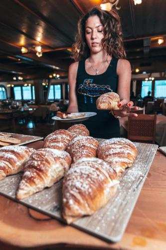 a woman standing behind a table with a tray of pastries at Sporting Hotel in Passo del Tonale