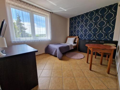 a bedroom with a bed and a table and a chair at Siedlisko Żurawie in Zamarte