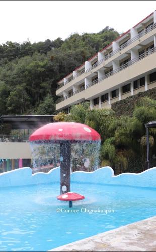 a red umbrella in the water in a swimming pool at Hotel y Aguas Termales de Chignahuapan in Chignahuapan