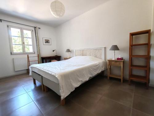 a bedroom with a bed and two tables and a window at Aix en Provence charmante villa piscine cadre verdoyant 6 personnes in Aix-en-Provence
