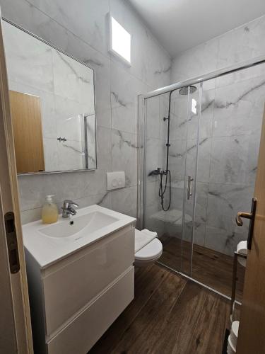 a white bathroom with a shower and a sink at Apartments Villa Šibenik in Primošten