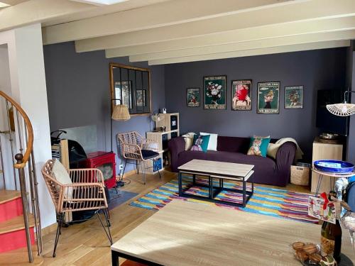 un salon avec un canapé violet et une table dans l'établissement Charmante petite maison de pays à 200 m du Golfe, à Sarzeau