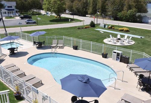 a swimming pool with umbrellas and tables and chairs at The Water Street Inn in Ephraim
