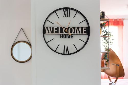 une horloge noire et blanche sur un mur avec un miroir dans l'établissement Paris Family & Friends - Gare à 5 Minutes - Parking, au Bourget