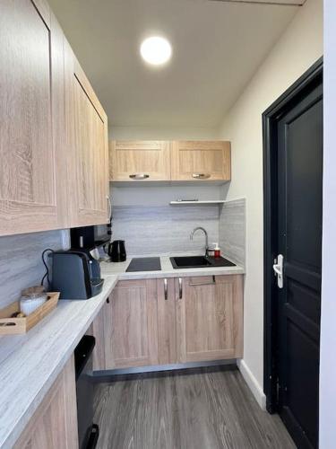 a small kitchen with wooden cabinets and a black door at Studio lumineux avec belle vue in Salernes