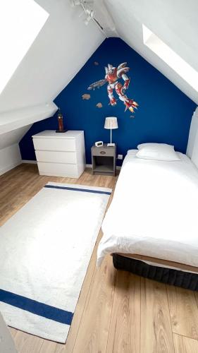 une chambre avec un mur bleu et une fresque murale représentant un super héros dans l'établissement Family apartment, next to Versailles Palace, à Buc