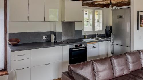 une cuisine avec des placards blancs et un canapé en cuir brun dans l'établissement Family apartment, next to Versailles Palace, à Buc