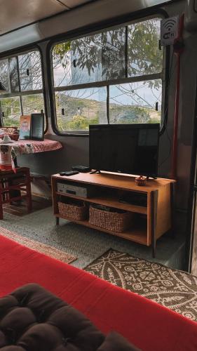 a living room with a flat screen tv in a van at Hospedagem Ônibus na Roça em Serra ES in Serra