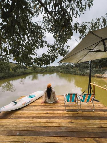 a man sitting on a dock next to a raft at Hospedagem Ônibus na Roça em Serra ES in Serra