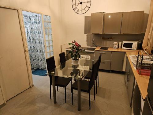 une cuisine avec une table, des chaises et une horloge murale dans l'établissement Marseille centre 6 personnes, à Marseille