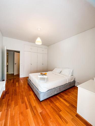 a bedroom with a large white bed and wooden floors at Spacious, Luxurious, and Charming Apartment in Premium Porto Location with PARKING in Porto