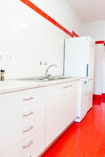 a white kitchen with a sink and a refrigerator at Spacious, Luxurious, and Charming Apartment in Premium Porto Location with PARKING in Porto