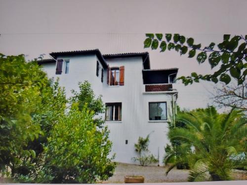 un bâtiment blanc avec des arbres devant dans l'établissement La Tuilerie, à Barcelonne-du-Gers