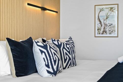 a bed with black and white pillows on it at Sun City - QStay in Gold Coast