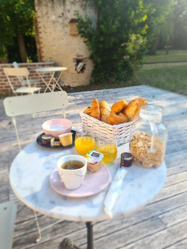 a picnic table with a basket of bread and drinks at Le Clos du Cèdre in Saint-Ouen