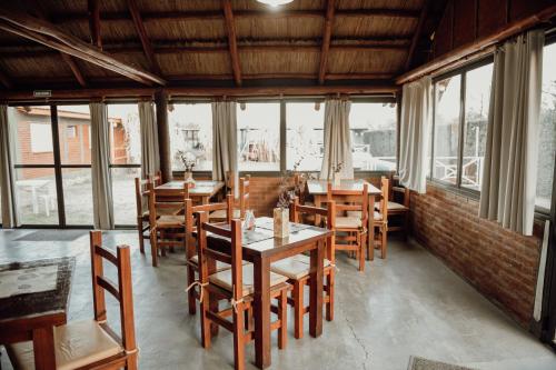 a dining room with tables and chairs and windows at Complejo Cantonavi in Mina Clavero