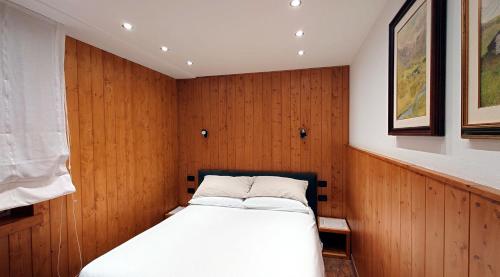 a bed in a room with wood paneling at Bilocale centro paese con posto auto in Madonna di Campiglio