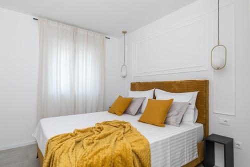 a white bedroom with a bed with yellow pillows at Villa AG in Podstrana