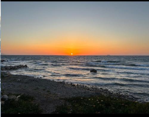 a sunset on the beach with the sun setting at Kamiros Apartment in Kalavárda