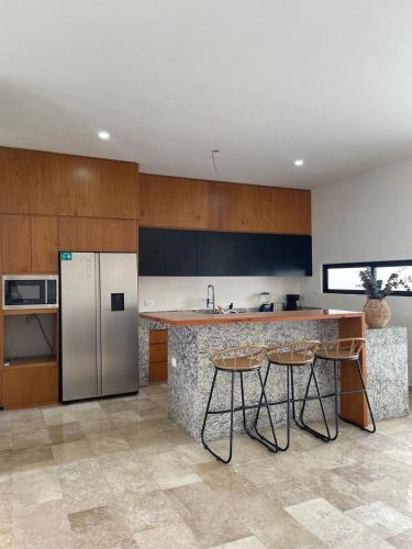 a kitchen with a refrigerator and a counter with stools at Comodidad y confort en casa Arennas in Mérida
