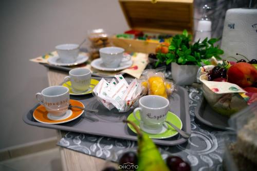 une table avec des tasses, des soucoupes et des fruits dessus dans l'établissement Corte Antica Luxury, à Ravanusa