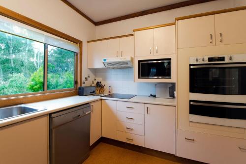 a kitchen with white cabinets and a window at Seascapes at Rosedale in Tomakin