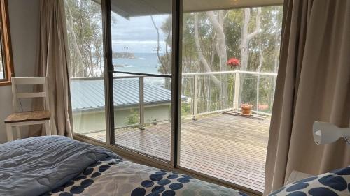 a bedroom with a large window with a view of a deck at Seascapes at Rosedale in Tomakin