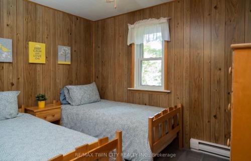 a bedroom with two beds and a window at Cozy Lakeside Cottage with Beautiful Sunsets in McDougall