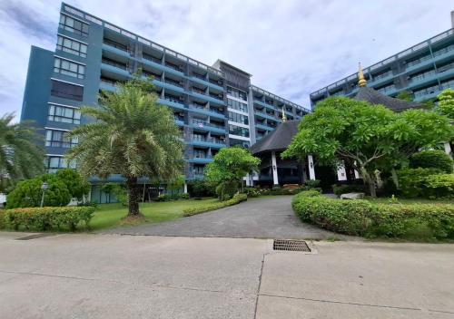 a large building with palm trees in front of it at Baan Bangsarey Hotels in Bang Sare