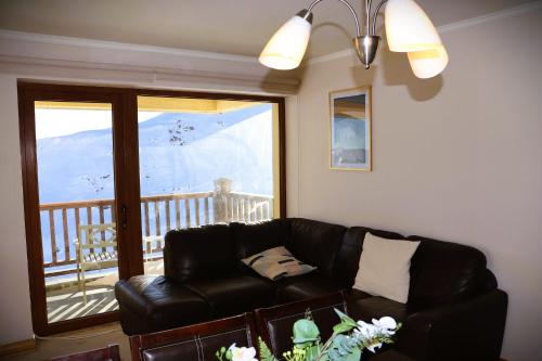 a living room with a leather couch and a balcony at HOM I Edificio Valle Blanco Valle Nevado 2D2B SKI IN&OUT in Farellones
