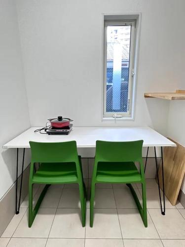 a white table with two green chairs and a window at 二条 秋 designer house 新築 2LDK 1階庭付き 4人宿泊可能 in Kyoto