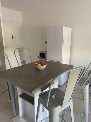 une table avec des chaises et un bol de fruits dessus dans l'établissement Appartement cosy avec terrasse, à Avignon