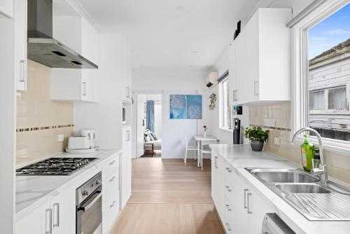 a kitchen with white cabinets and a large window at Elegant Double Room at Botany - Mins to Airport - Shared Bathroom in Sydney