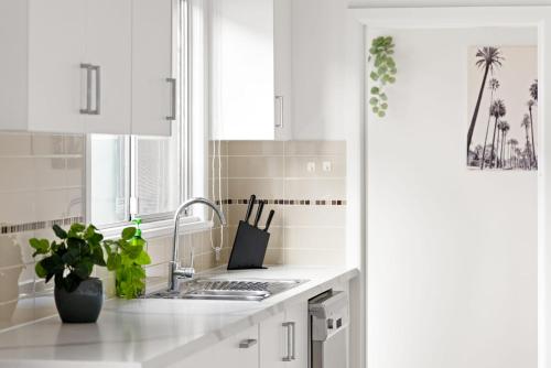 a white kitchen with a sink and a window at Elegant Double Room at Botany - Mins to Airport - Shared Bathroom in Sydney