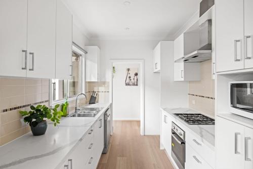 a white kitchen with white cabinets and appliances at Elegant Queen Room at Botany - Nearby Airport - Shared Bathroom in Sydney