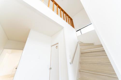 a staircase in a house with white walls and wooden floors at Miraie Yokkaichi Aobacho in Yokkaichi