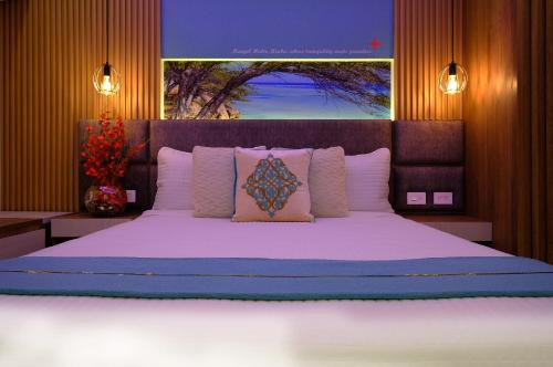 a bedroom with a large bed with pink pillows at Victoria City Hotel in Oranjestad