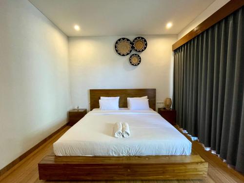 une chambre avec un lit et une horloge murale dans l'établissement Luana Villa Ubud, à Ubud