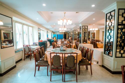 a restaurant with tables and chairs in a room at Le President Hotel in Phnom Penh