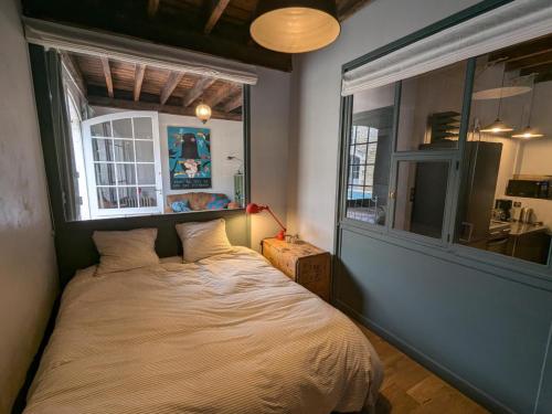 a bed in a room with a large window at Appartement historique avec piscine, salle de jeux, et jardin - idéal famille et amis - FR-1-653-261 in Angoulême