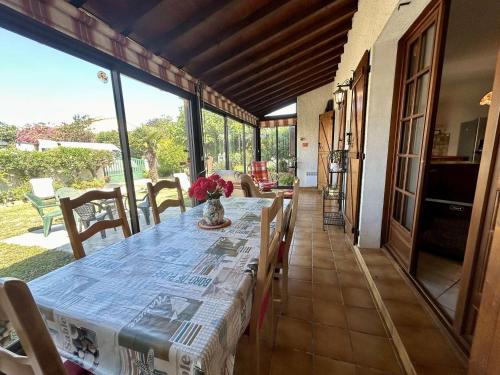 une salle à manger avec une table avec vue sur la cour dans l'établissement Villa familiale climatisée avec jardin, proche plage, parking, Wifi et barbecue - Saint-Cyprien - FR-1-225D-218, à Saint-Cyprien