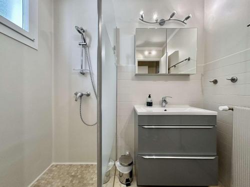 une salle de bain avec une douche, un lavabo et un miroir dans l'établissement Charmant T2 rénové, balcon sud, proche commerces - FR-1-330F-238, au Monêtier-les-Bains