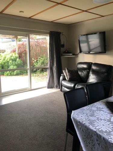 a living room with a leather couch and a television at Down South Cottage in Invercargill