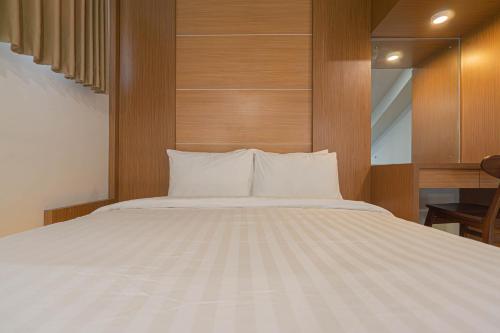 a bedroom with a white bed with a wooden wall at Casa Residence Bali By Bali Cabin in Kerobokan