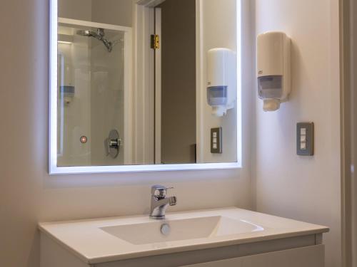 a bathroom with a white sink and a mirror at Paroa Hotel in Greymouth
