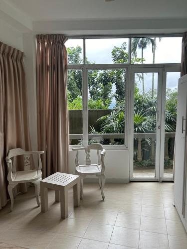 a living room with two chairs and a large window at Range Kandy in Kandy