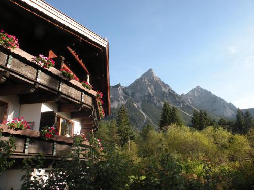 a building with flowers on it with mountains in the background at Tyrol Appartements in Ehrwald